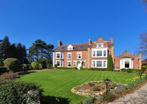 a large brick house with a green lawn at Church Beck Retreat in Scalby