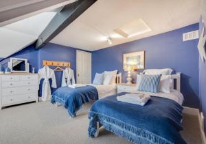 a blue bedroom with two beds and a tv at Church Beck House in Scalby