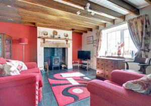 a living room with two red couches and a fireplace at Cheyne Cottage in Hawsker
