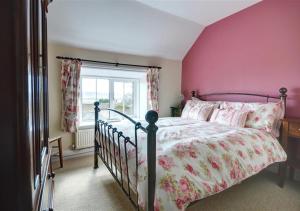 a bedroom with a bed with pink walls and a window at Cheyne Cottage in Hawsker