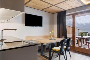 a kitchen and dining room with a table and a tv at Angerle Alm Apt Similde A in Carezza al Lago