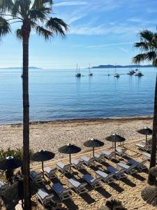 un grupo de tumbonas y sombrillas en una playa en Hotel La Potiniere, en Hyères