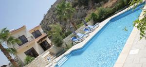 a swimming pool with lounge chairs in front of a mountain at A three-bedroom villa with a private pool and landscaped garden Wi-Fi in Pissouri