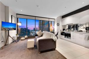 Opulent Level 25 Condo with Breathtaking Views في ملبورن: غرفة معيشة مع أريكة ونافذة كبيرة