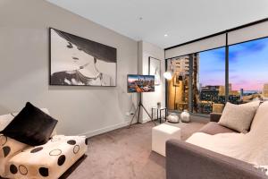 Opulent Level 25 Condo with Breathtaking Views في ملبورن: غرفة معيشة مع أريكة ونافذة كبيرة