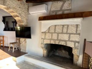 chimenea de piedra con TV en la pared en Romanos Villa, en Pafos