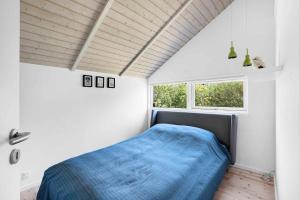 a bedroom with a blue bed and a window at Beautiful Holiday Home In North Zealand in Tikøb