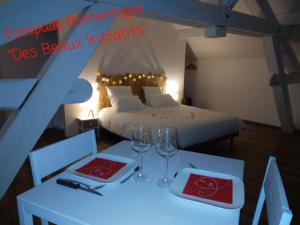 1 dormitorio con 1 cama y 2 mesas con copas de vino en Des Beaux Instants, en Soulosse-sous-Saint-Élophe