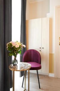 una silla púrpura sentada junto a una mesa con un jarrón de flores en AR Apartamenty, en Poznan