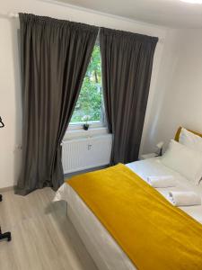 ブカレストにあるTriumf Apartmentのベッドルーム1室(黄色い毛布と窓付)