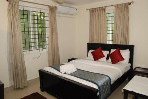 班加罗尔The Altruist Business Stays, Manayata Tech Park的卧室里有一张大床，配有红色枕头