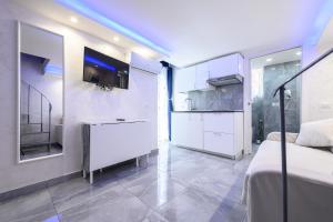 a white room with a bed and a kitchen at La magnifica napoli apartments gold house in Naples