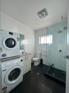 a bathroom with a washing machine and a toilet at Beach apartment 10/22 esplanade sea-views in Glenelg