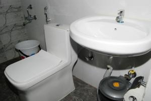 een badkamer met een wit toilet en een wastafel bij The Altruist Business Stays, Manayata Tech Park in Bangalore