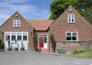a red brick house with a red door at Call Out Cottage in Sledmere