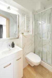 a white bathroom with a toilet and a shower at AR Apartamenty in Poznań