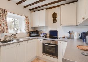 a kitchen with white cabinets and a stove top oven at Buttercup Cottage in Tosside
