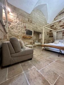 a living room with a couch and a stone wall at Petra Oikia Apartments in Corigliano dʼOtranto