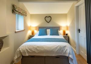 a bedroom with a large bed with blue pillows at Button Cottage in Bellerby