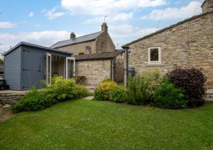 an old stone house with a garden in front of it at Button Cottage in Bellerby