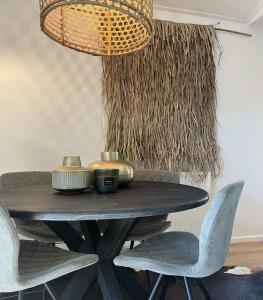 mesa de comedor con sillas y lámpara de araña en Wellness Cabin Nulytø 24, en Rheezerveen
