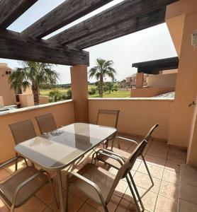 d'une table et de chaises sur un balcon avec des palmiers. dans l'établissement Villanueva Golf- Cozy 2 Bedrooms -Puerto Real, Cádiz, à Puerto Real