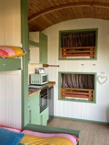 a kitchen with green and white cabinets and a microwave at Dune Shepherds Hut in Penally