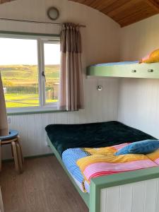 a bunk bed in a small room with a window at Dune Shepherds Hut in Penally