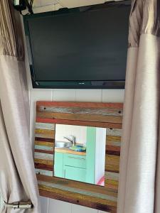 a bathroom mirror with a sink and a tv at Dune Shepherds Hut in Penally