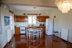 Una cocina con una mesa y un refrigerador blanco. en SEA & OLIVES HOUSE, en Lixouri
