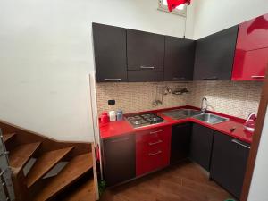 Elle comprend une petite cuisine avec des placards rouges et un évier. dans l'établissement L’antico casale, à Reggio de Calabre