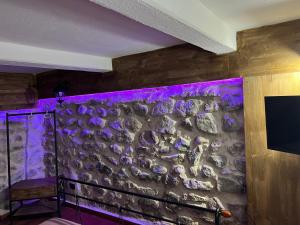 - un mur en pierre dans une chambre avec des lumières violettes dans l'établissement L’antico casale, à Reggio de Calabre