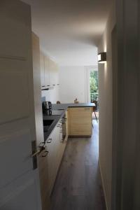 a kitchen with white cabinets and a wooden floor at La petite Rascasse, Appartement avec Terrasse ensoleillée in Rayol-Canadel-sur-Mer