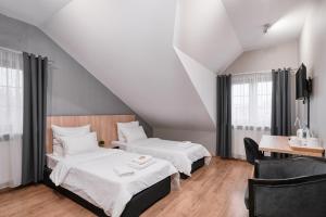 a bedroom with two beds and a table and chairs at Artis Dom Gościnny in Zamość +27 photos