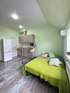 a bedroom with a green bed and a refrigerator at Central Park Apartment on Sumskaya in Kharkiv