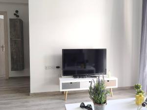 a flat screen tv sitting on a white stand in a living room at Pegasus Amazing Flat, 15min Walk To The Beach in Chania Town