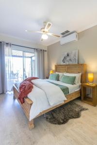 a bedroom with a large bed with a ceiling fan at Feather Nest Guest House in Oudtshoorn