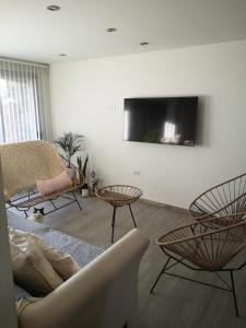 sala de estar con sillas y TV en la pared en Valen House en Malargüe