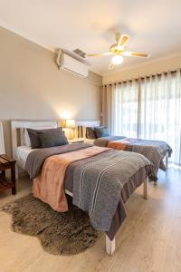 a bedroom with two beds and a ceiling fan at Feather Nest Guest House in Oudtshoorn