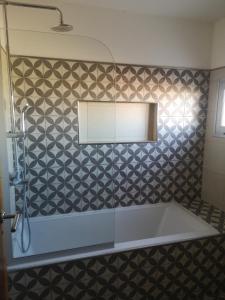 y baño con bañera y pared de azulejos. en Valen House en Malargüe