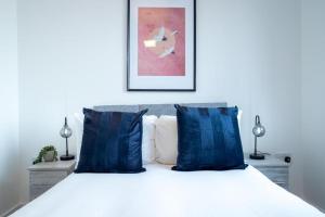a bedroom with a white bed with blue pillows at Bayard Apartments - Duplex Penthouse Apartment in Peterborough