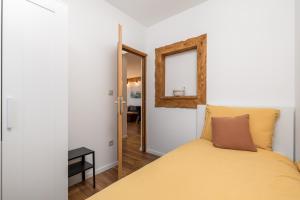 a bedroom with a yellow bed and a mirror at Apartman Roko in Vrata