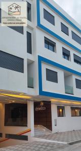 a white and blue building with a garage at Appartement à la plage Mehdia pour famille uniquement in Kenitra