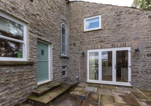 a brick house with a green door and windows at Beech House in Hawes