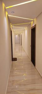 un pasillo con paredes blancas y un largo pasillo con luces amarillas en Appartement à la plage Mehdia pour famille uniquement, en Kenitra