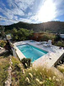 a swimming pool in a yard with the sun shining at Cabañas Namaskar in Villa Serranita