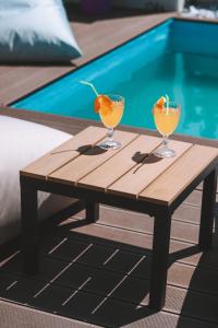 two glasses on a wooden table next to a pool at Sithon Diamond Suites 1 in Nikiti