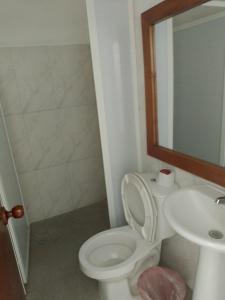 y baño con aseo, lavabo y espejo. en Hostería Altamar Tolú, en Tolú