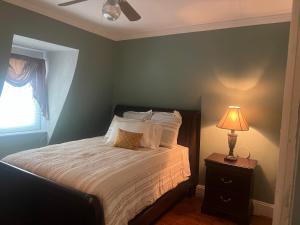 a bedroom with a bed with a lamp and a window at Private Victorian Apartment in convenient City location on 5 acre, Sleeps 5 in Poughkeepsie