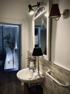 a bathroom with a sink and a mirror and a lamp at La Casita del Abuelo Valentín 
